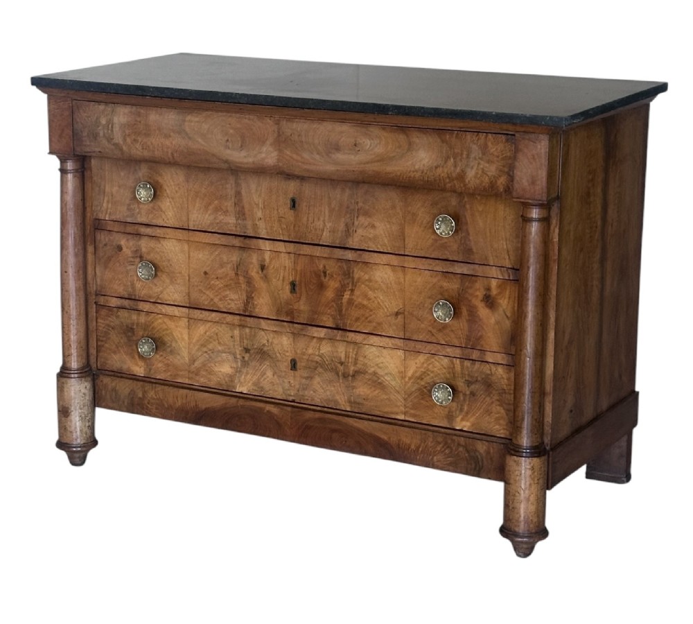 A 19th-century French Charles X walnut commode featuring three lower drawers with round metal pulls, flanked by architectural side columns and topped with a dark marble slab. View III