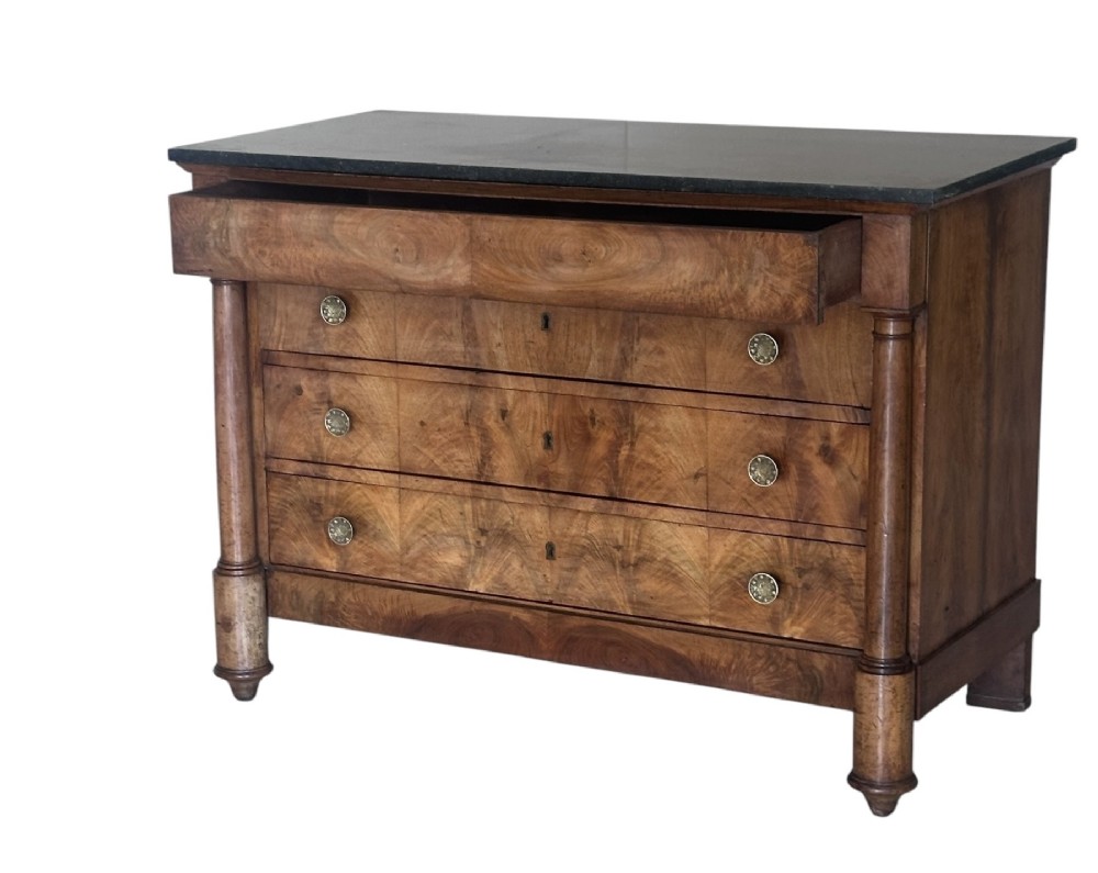 A 19th-century French Charles X walnut commode featuring three lower drawers with round metal pulls, flanked by architectural side columns and topped with a dark marble slab. View IV