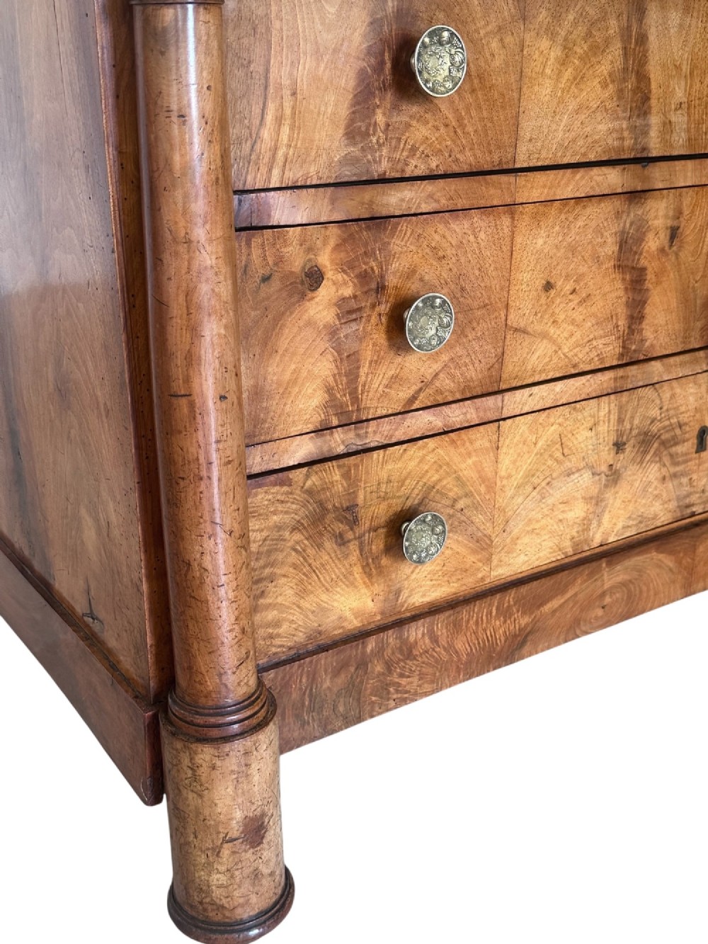 A 19th-century French Charles X walnut commode featuring three lower drawers with round metal pulls, flanked by architectural side columns and topped with a dark marble slab. View VII