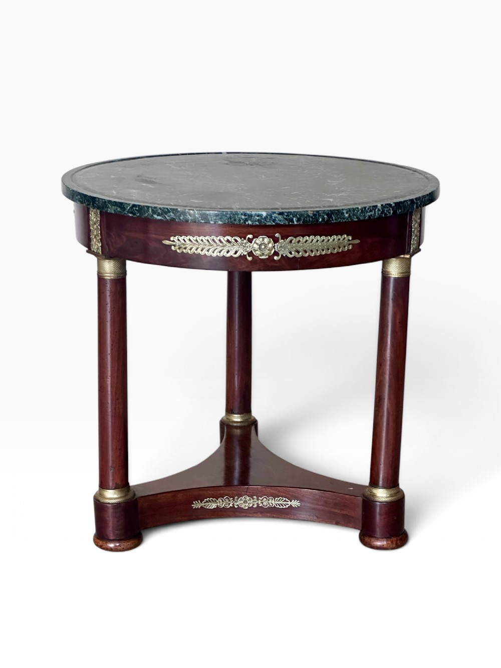 A 19th-century French Empire circular centre table featuring a dark green marble top, mahogany column legs with gilt-bronze mounts, and a triform base.