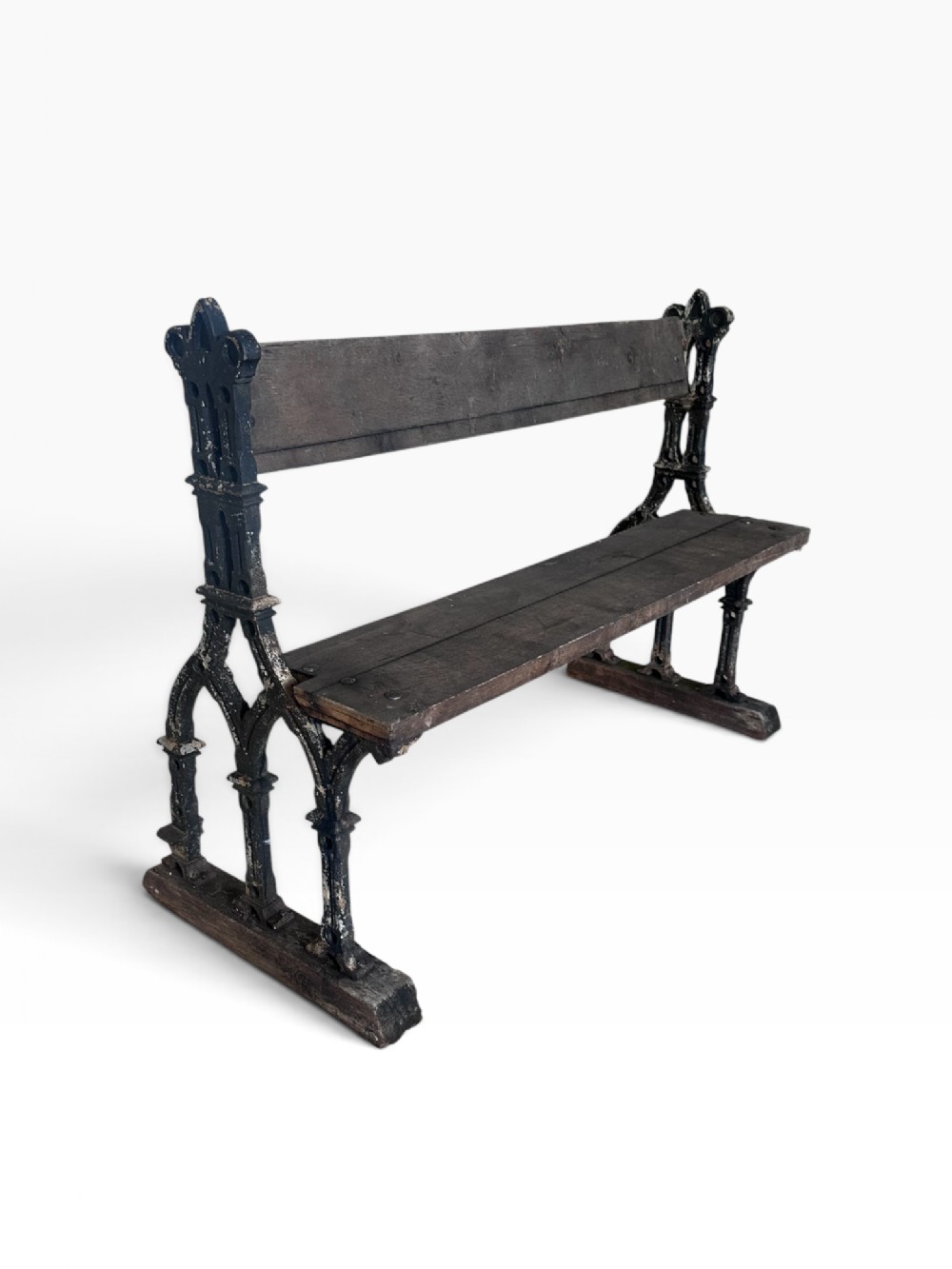 A 19th-century Victorian Gothic cast iron garden bench with black painted traceried ends and dark weathered wooden seat slats.