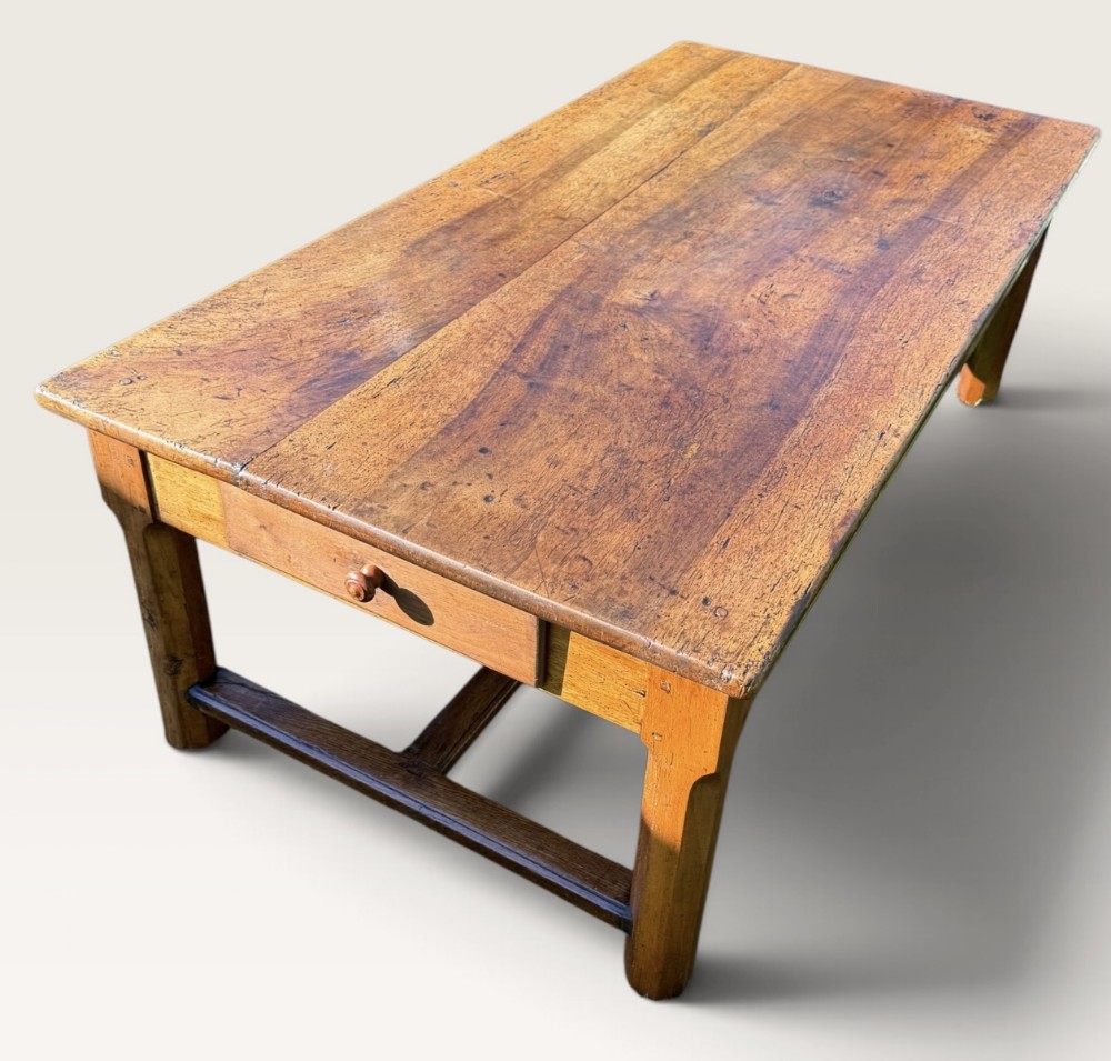 A large rectangular antique walnut coffee table with a single end drawer, turned wooden knob, and low wooden stretchers between sturdy legs.