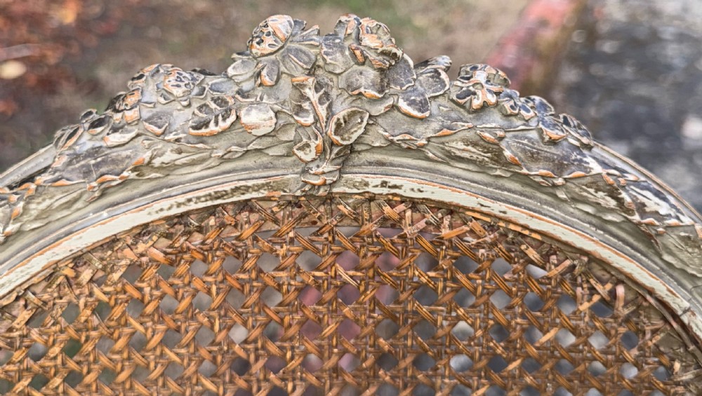A pair of French Louis XVI style side chairs with oval cane backs, woven cane seats, distressed painted frames, and turned fluted legs. View III