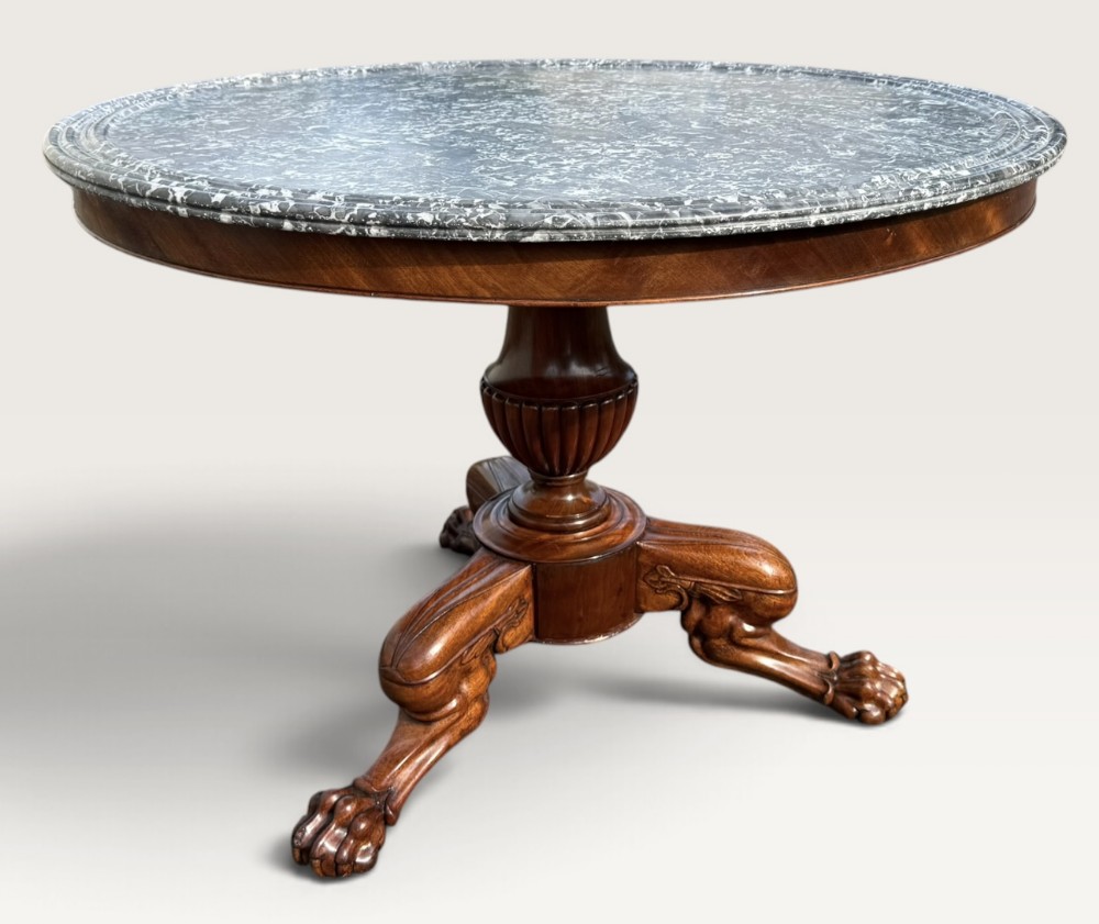 An early nineteenth-century mahogany centre table featuring a round grey marble top, fluted central pedestal, and tripod legs with carved paw feet.