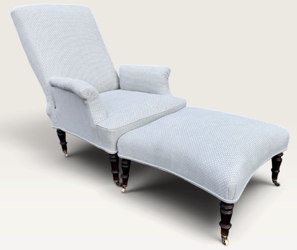 A 19th-century French reclining armchair and matching contoured footstool upholstered in pale blue woven fabric with dark turned wood legs on brass castors. View II