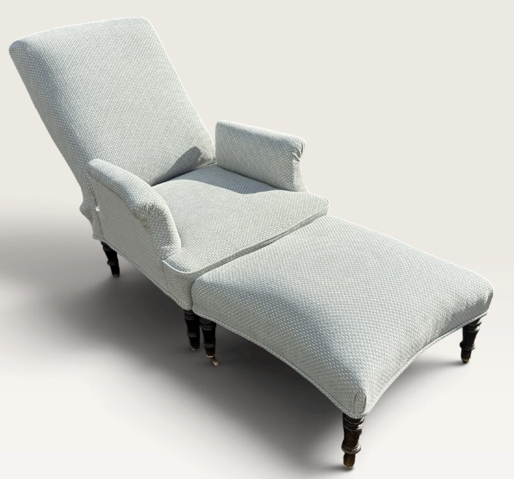 A 19th-century French reclining armchair and matching contoured footstool upholstered in pale blue woven fabric with dark turned wood legs on brass castors. View VII