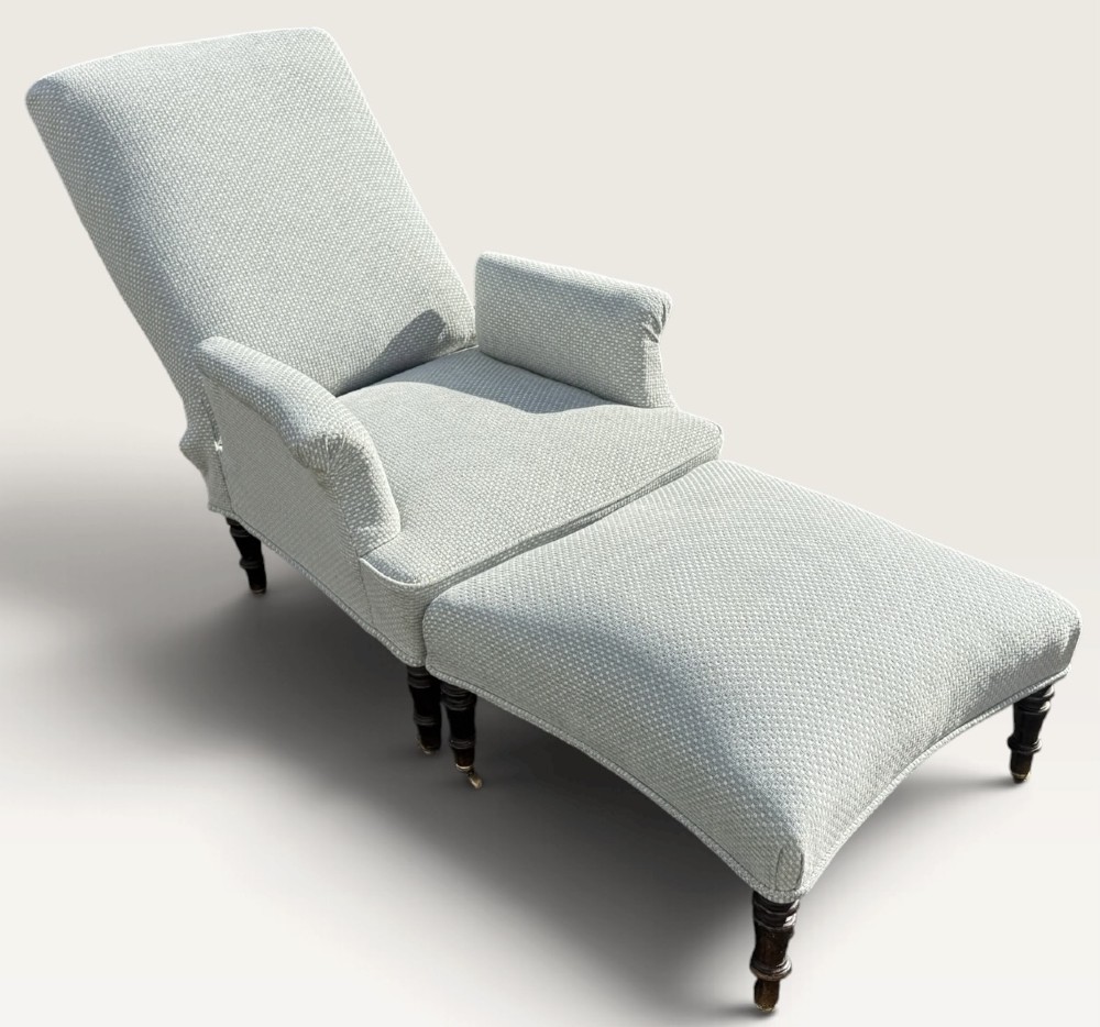 A 19th-century French reclining armchair and matching contoured footstool upholstered in pale blue woven fabric with dark turned wood legs on brass castors. View VIII