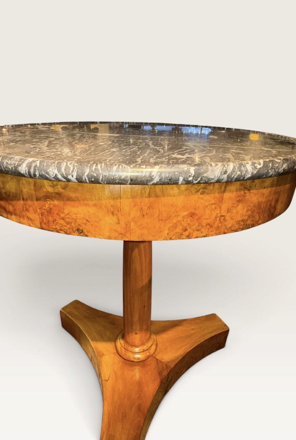 A circular antique centre table featuring a grey veined marble top, burr walnut veneered apron, a central turned column, and a triform platform base. View III