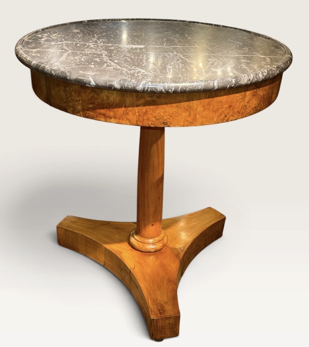 A circular antique centre table featuring a grey veined marble top, burr walnut veneered apron, a central turned column, and a triform platform base. View VII