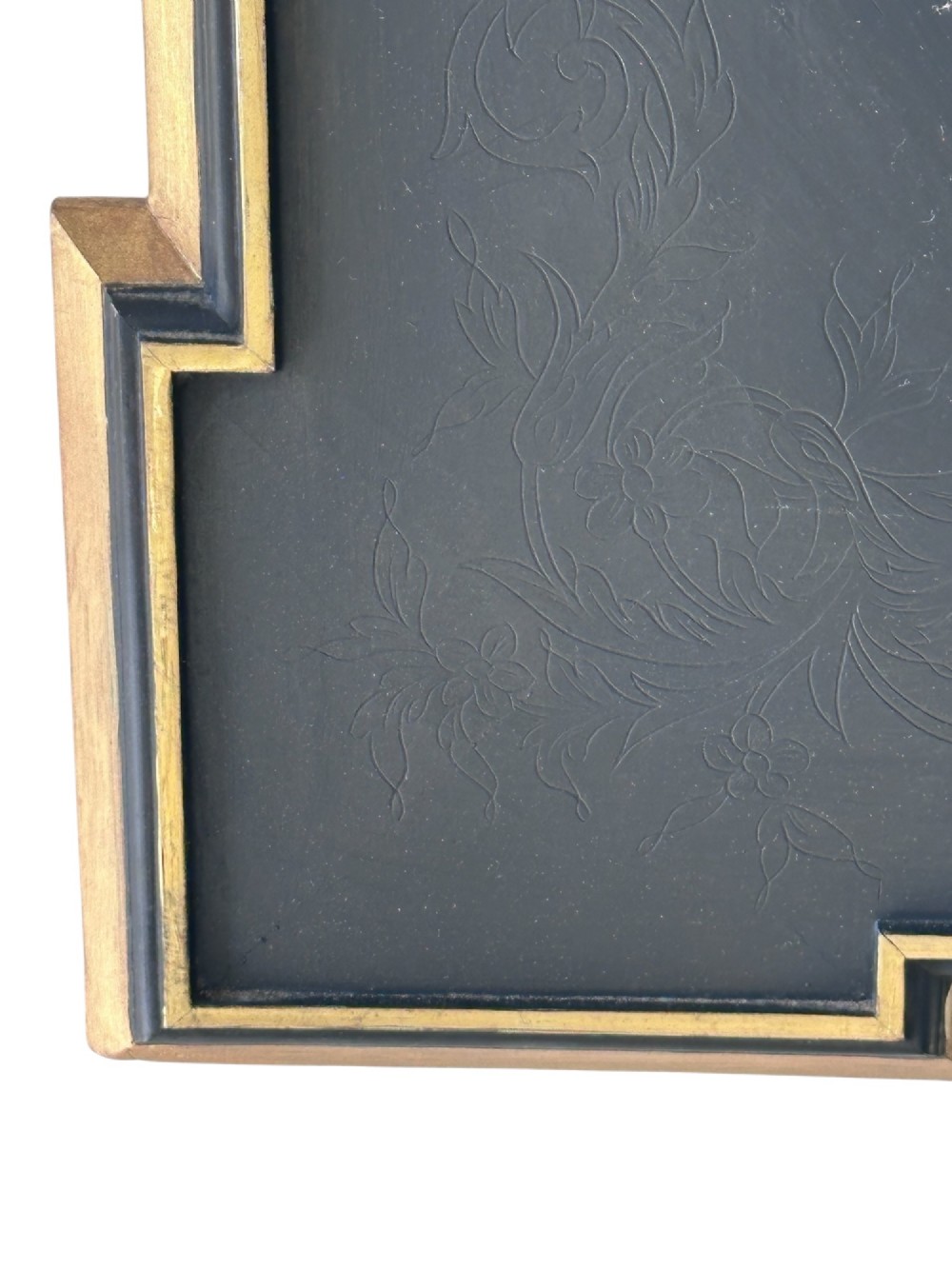 A rectangular black framed mirror with indented corners, gold leaf moulding, and a central oval mirror plate bordered by gilded floral patterns. View II