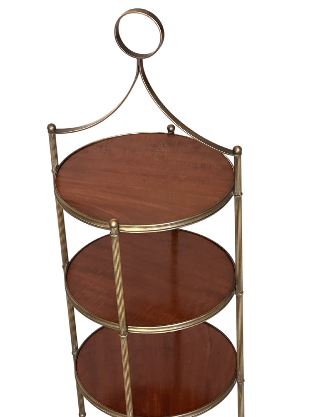 An early 20th-century three-tiered mahogany and brass etagere featuring reeded metal supports and a top carrying ring. View II