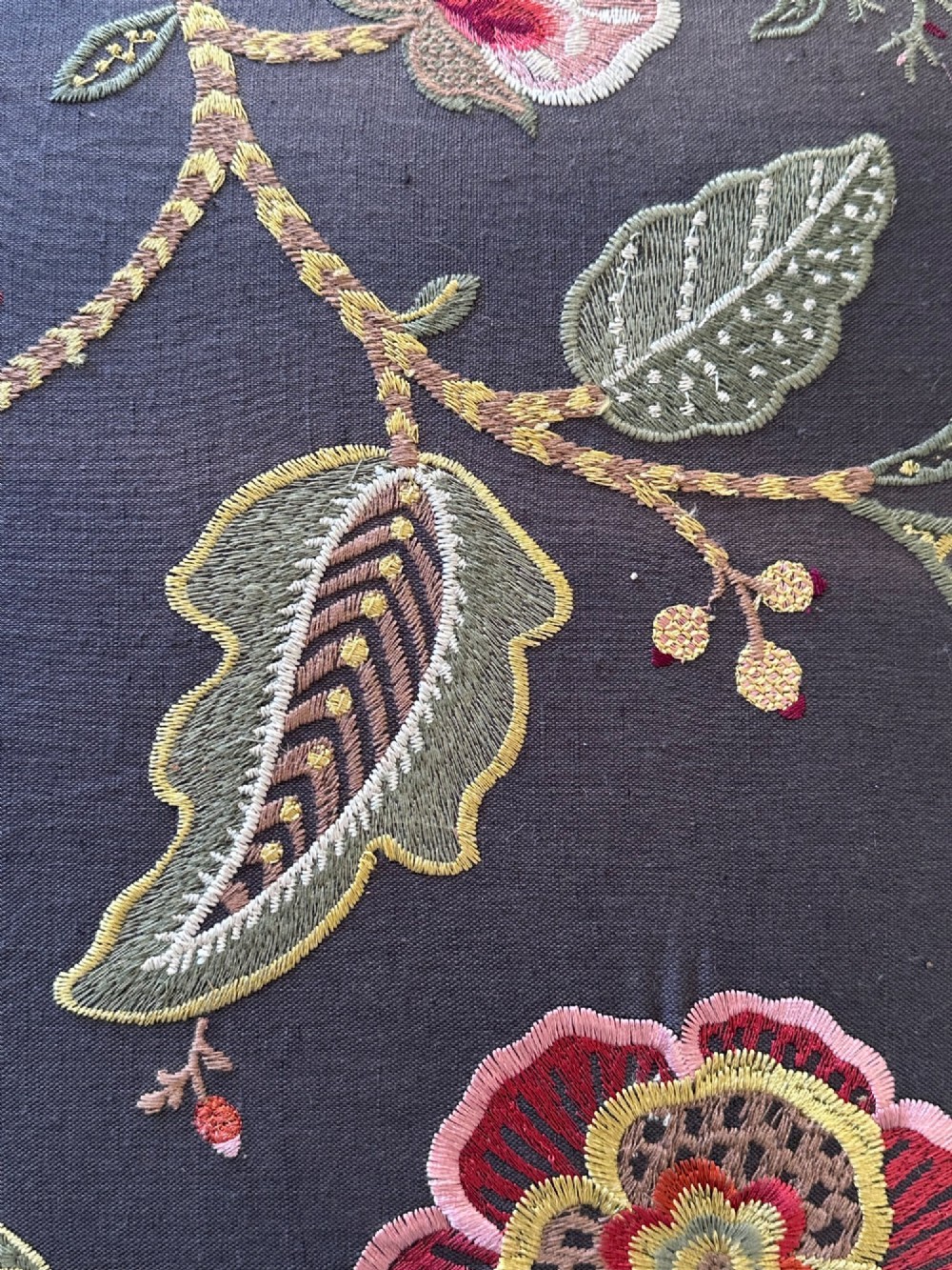 A 19th-century William and Mary style walnut stool featuring turned legs, a curved X-frame stretcher, and dark upholstered top embroidered with colourful floral motifs. View V