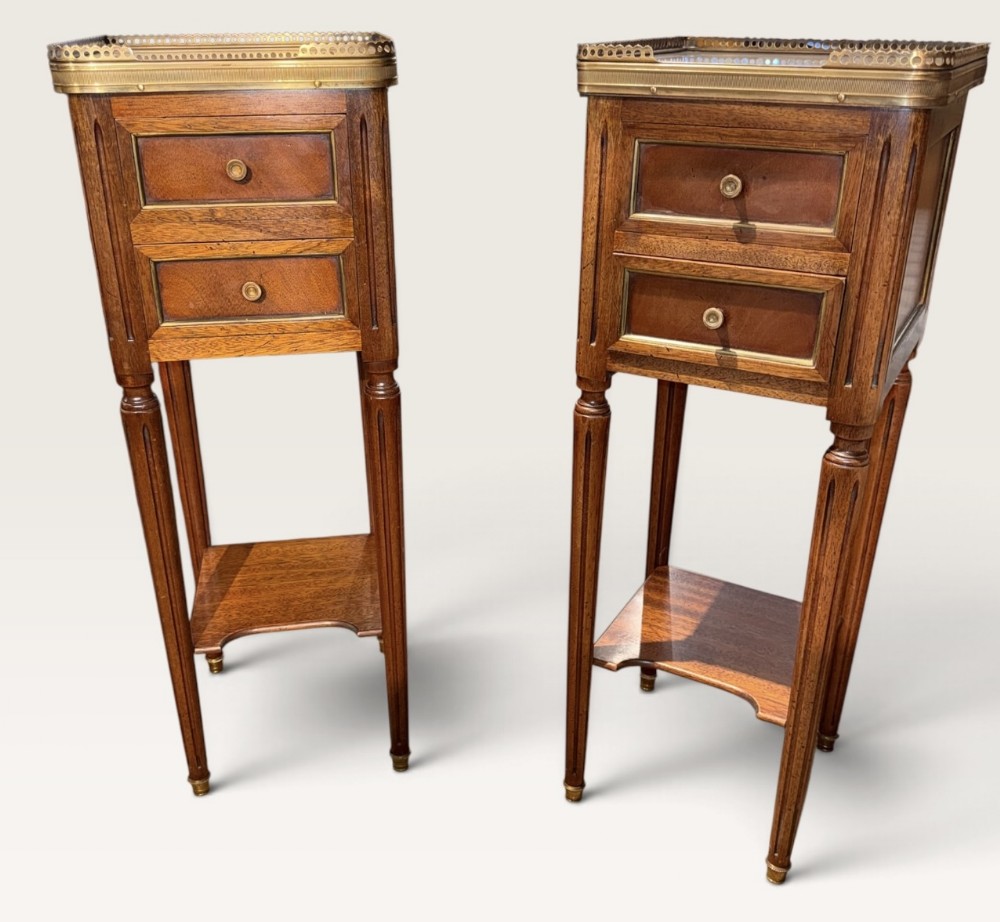 Pair of tall, slender French dark wood bedside tables with two drawers, lower tier shelves, turned fluted legs, and brass gallery rims.