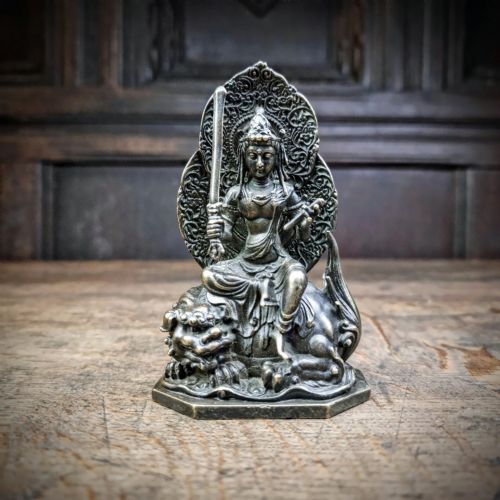 A small 19th-century patinated bronze figure depicting a deity seated upon a mythical lion with an openwork mandorla backdrop. View II