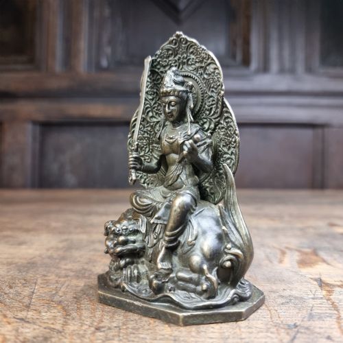 A small 19th-century patinated bronze figure depicting a deity seated upon a mythical lion with an openwork mandorla backdrop. View IV