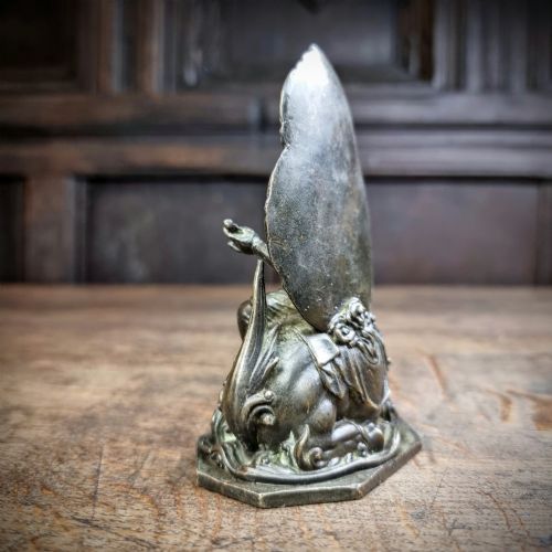 A small 19th-century patinated bronze figure depicting a deity seated upon a mythical lion with an openwork mandorla backdrop. View V