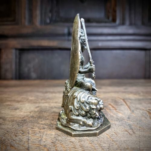 A small 19th-century patinated bronze figure depicting a deity seated upon a mythical lion with an openwork mandorla backdrop. View VII