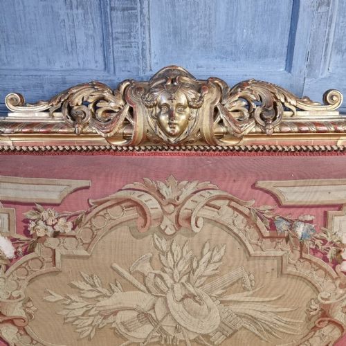 A 19th-century giltwood settee featuring detailed frame carvings, padded armrests, and distressed floral tapestry upholstery. View V