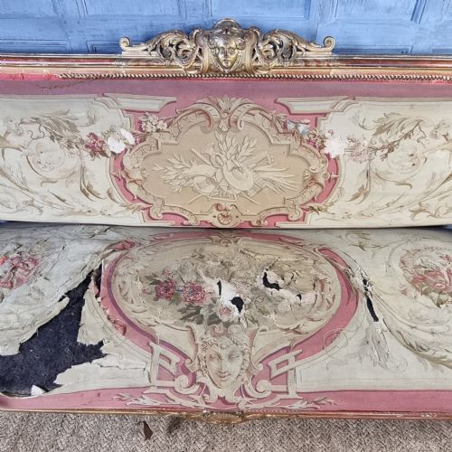 A 19th-century giltwood settee featuring detailed frame carvings, padded armrests, and distressed floral tapestry upholstery. View VI