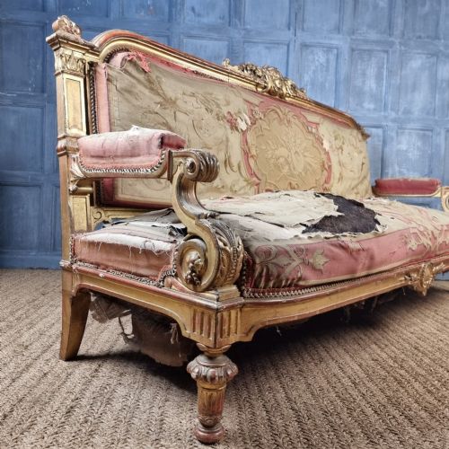 A 19th-century giltwood settee featuring detailed frame carvings, padded armrests, and distressed floral tapestry upholstery. View IX