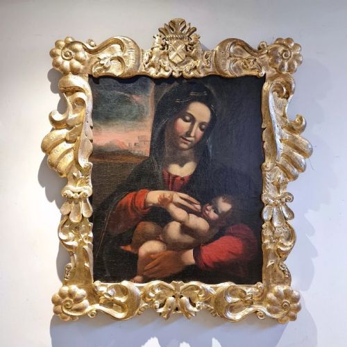 fig 1. An oil painting depicting the Madonna and Child housed in a carved gold giltwood frame with a top crest.