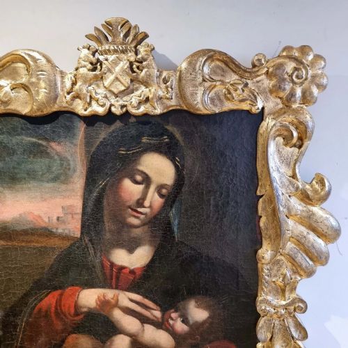 An oil painting depicting the Madonna and Child housed in a carved gold giltwood frame with a top crest. View V