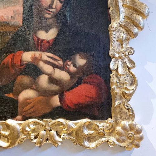 An oil painting depicting the Madonna and Child housed in a carved gold giltwood frame with a top crest. View VI