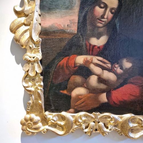 An oil painting depicting the Madonna and Child housed in a carved gold giltwood frame with a top crest. View VII