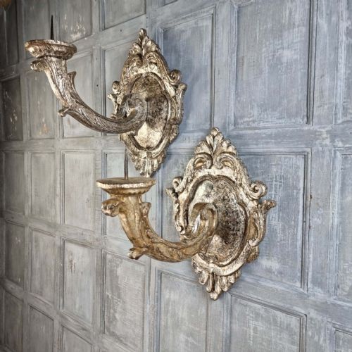 A pair of 17th-century carved wood wall sconces with silvered gilding, featuring ornate cartouche backplates, scrolling arms, and iron prickets. View III