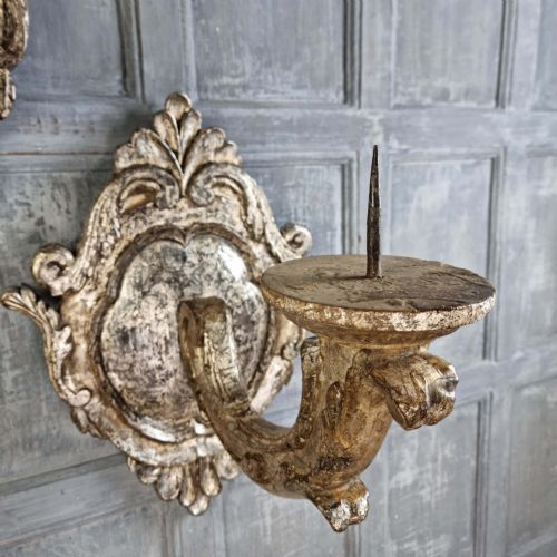 A pair of 17th-century carved wood wall sconces with silvered gilding, featuring ornate cartouche backplates, scrolling arms, and iron prickets. View IV
