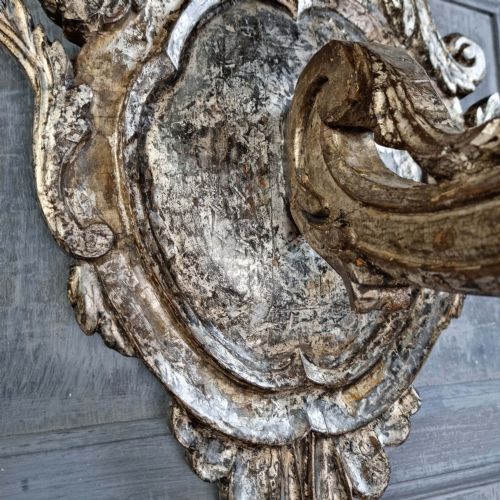 A pair of 17th-century carved wood wall sconces with silvered gilding, featuring ornate cartouche backplates, scrolling arms, and iron prickets. View VII