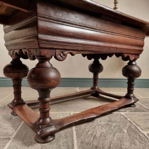 fig 1. A dark oak seventeenth-century refectory dining table with extensible draw leaves, bulbous turned legs, and a floor-level perimeter stretcher.