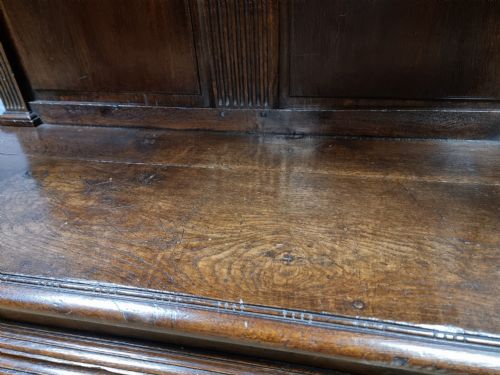 A dark carved oak cupboard featuring two relief-carved doors with figure motifs, upper drawers with ring handles, fluted columns, and an open lower tier. View VIII