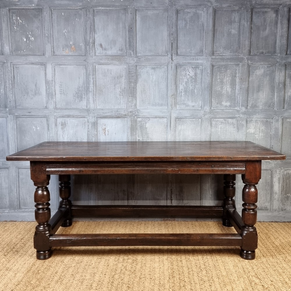 A long dark oak 17th century refectory table featuring a carved frieze along the apron, turned legs, and a sturdy low stretcher base. View XIII