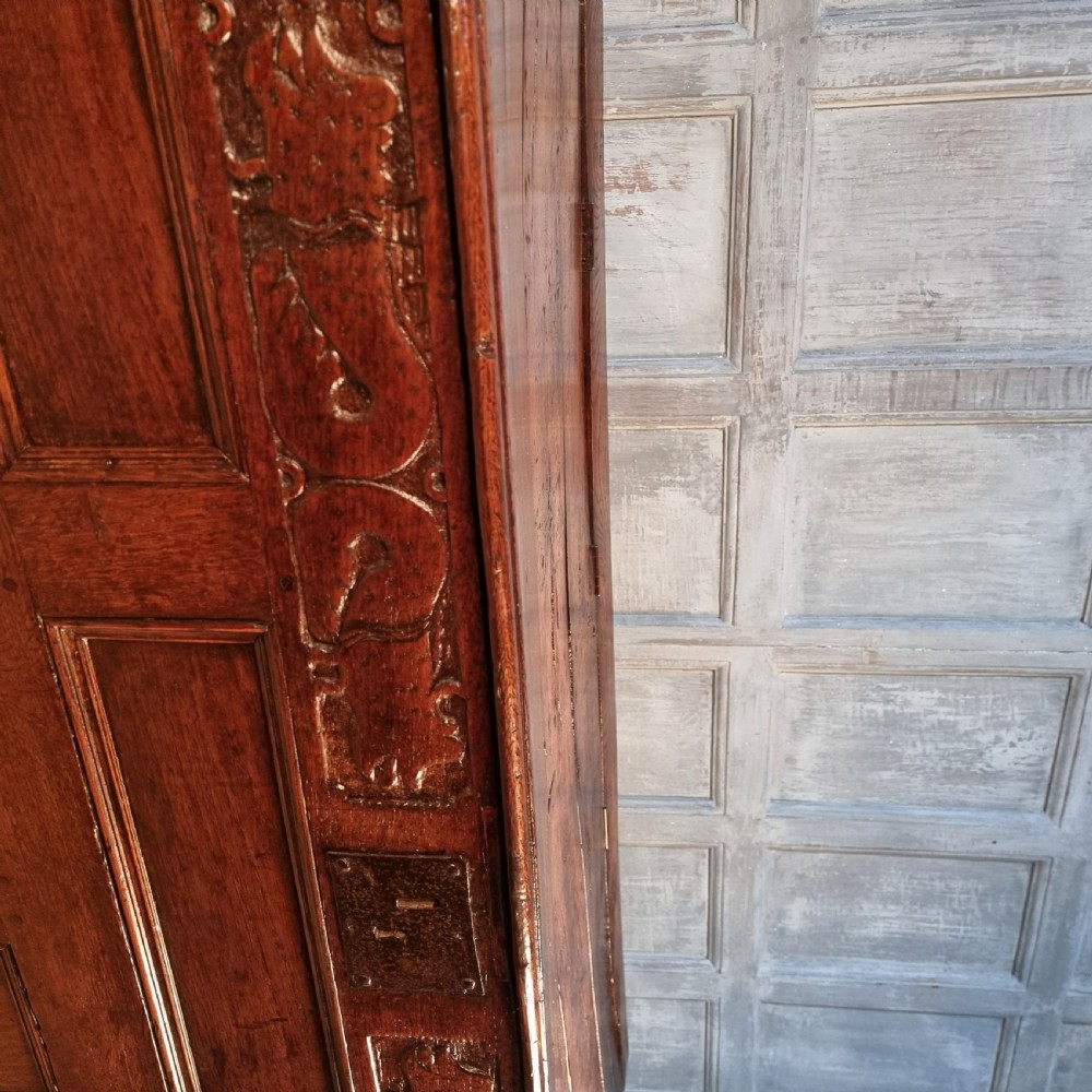 A large 17th-century dark oak coffer featuring hand-carved frieze panels, raised lower panelling, and a central iron lock plate. View XI