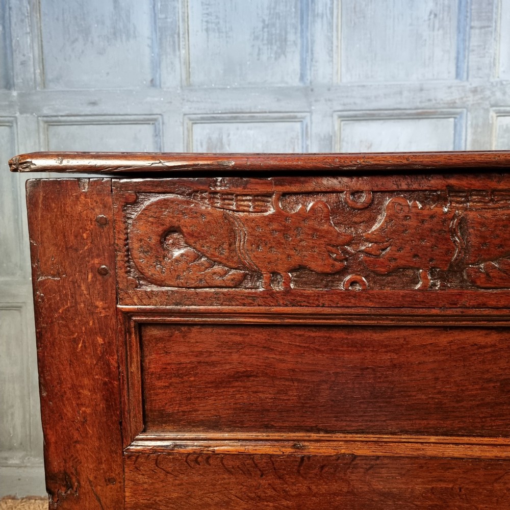 A large 17th-century dark oak coffer featuring hand-carved frieze panels, raised lower panelling, and a central iron lock plate. View III