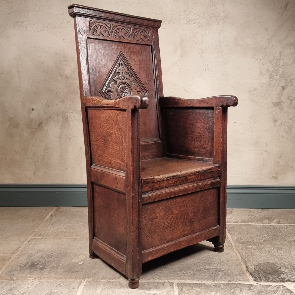 A 17th-century carved dark oak armchair featuring a high back with a central diamond lozenge motif, arcaded carving, and an enclosed box base. View IV