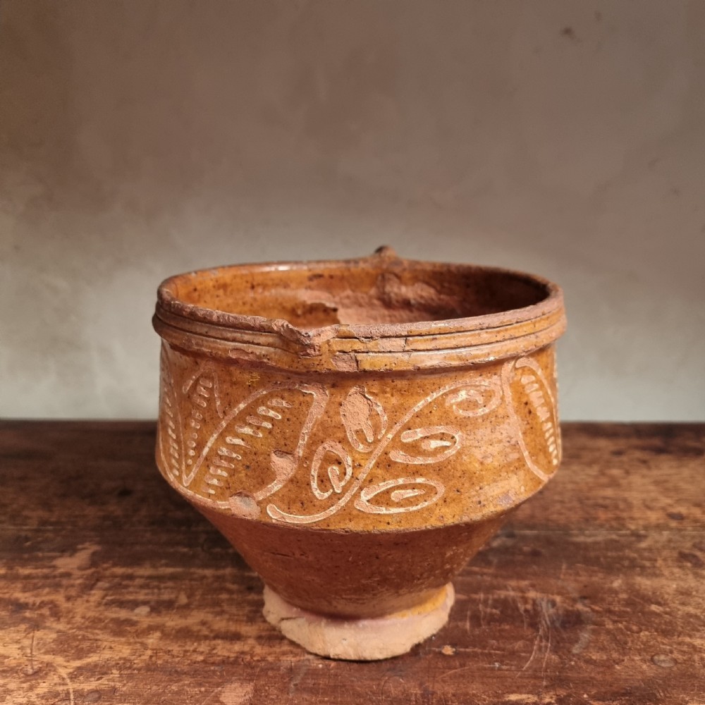 A seventeenth-century Dutch earthenware jug featuring an ochre glaze, a side loop handle, and white trailed slipware leaf patterns. View VIII