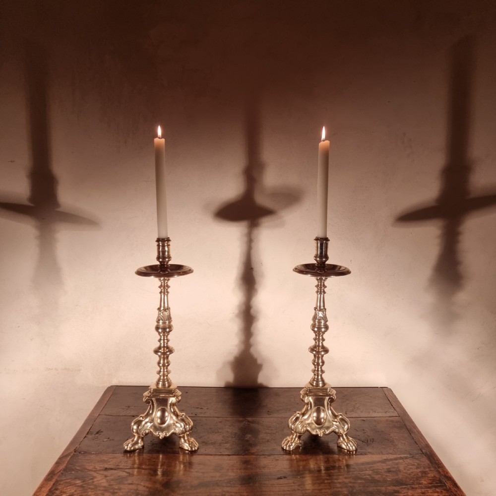 A pair of tall 19th-century brass candlesticks featuring knopped stems, drip pans, and ornate triform claw-foot bases. View II