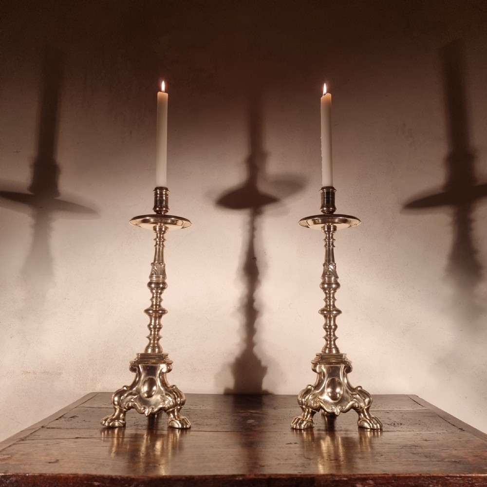 A pair of tall 19th-century brass candlesticks featuring knopped stems, drip pans, and ornate triform claw-foot bases. View IV