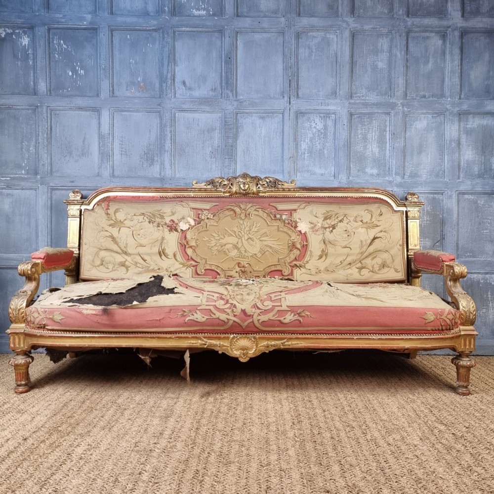 A 19th-century giltwood settee featuring detailed frame carvings, padded armrests, and distressed floral tapestry upholstery. View III
