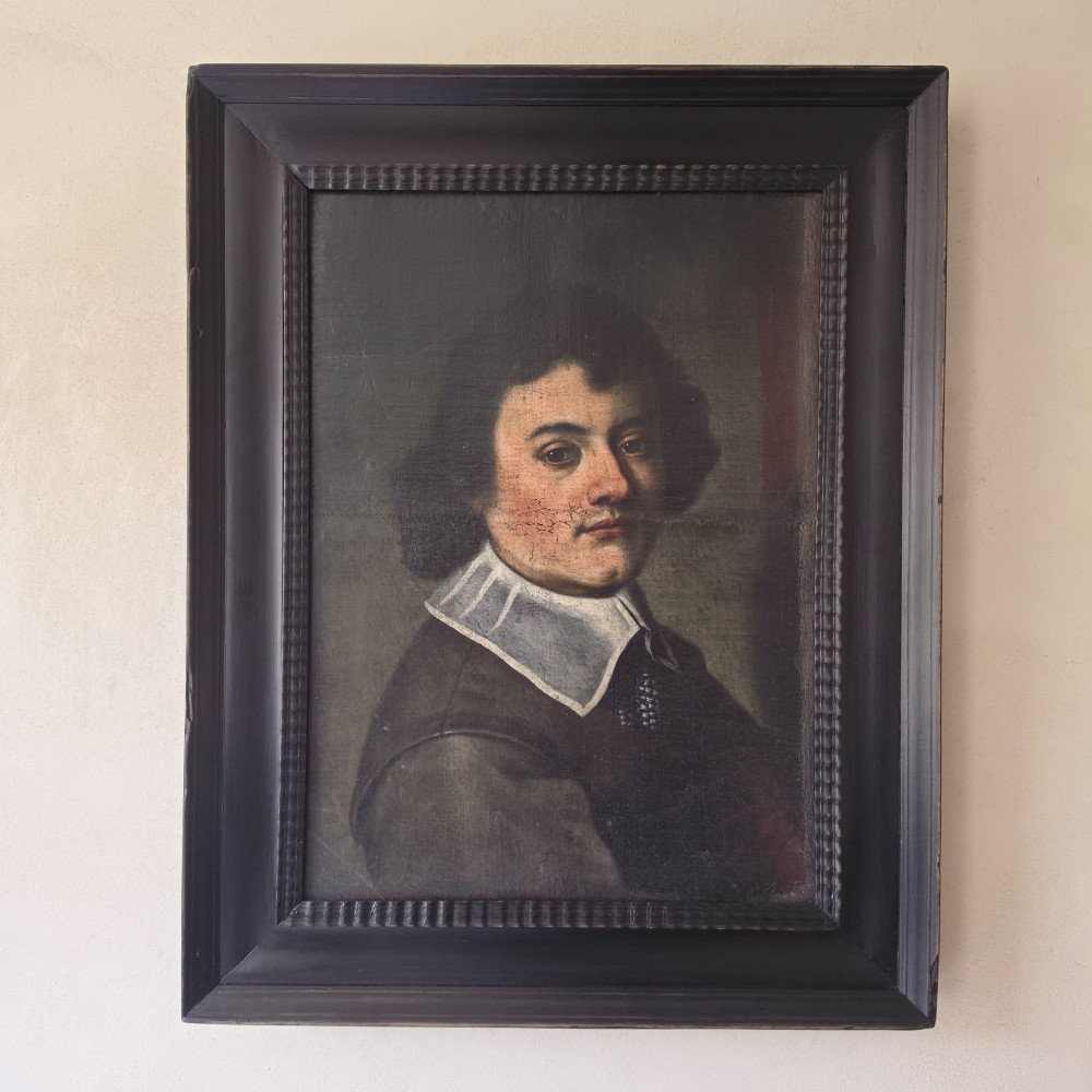 An antique oil painting depicting a 17th-century gentleman with dark hair and a white collar, presented in a dark ebonised frame.