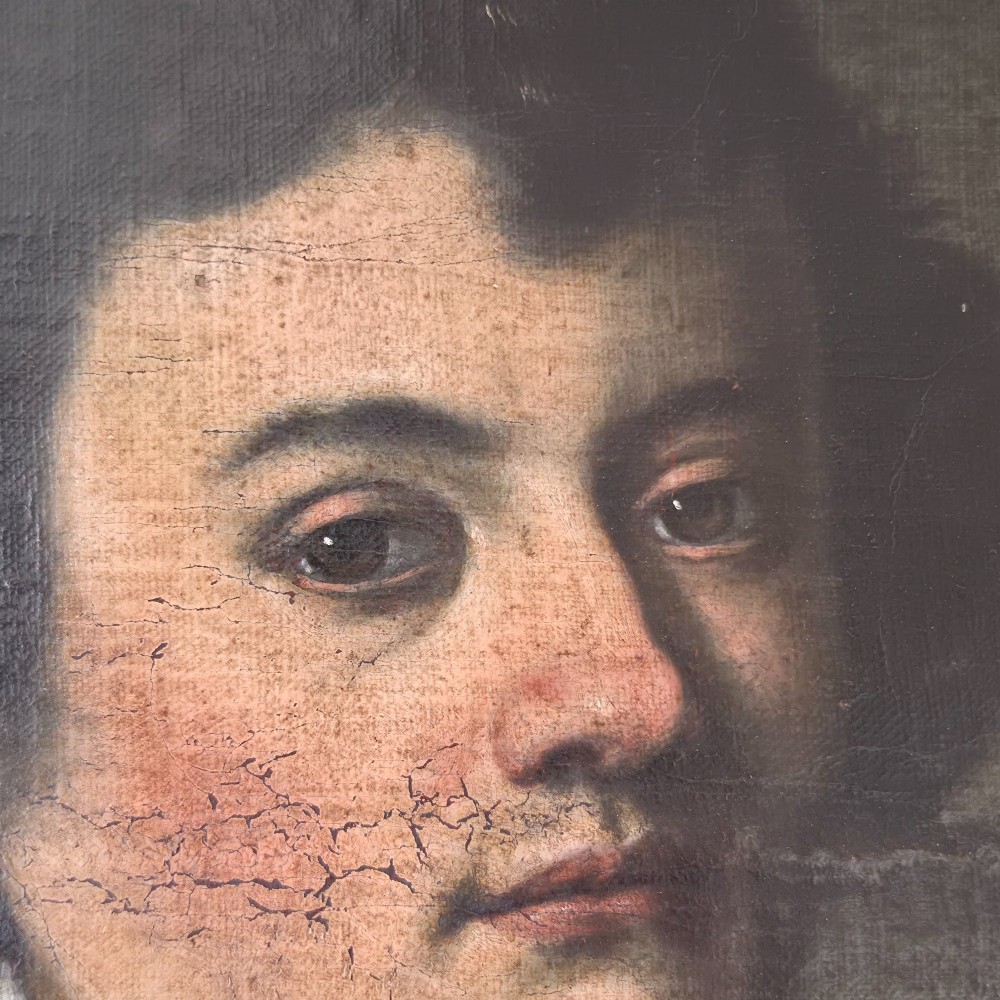 An antique oil painting depicting a 17th-century gentleman with dark hair and a white collar, presented in a dark ebonised frame. View III