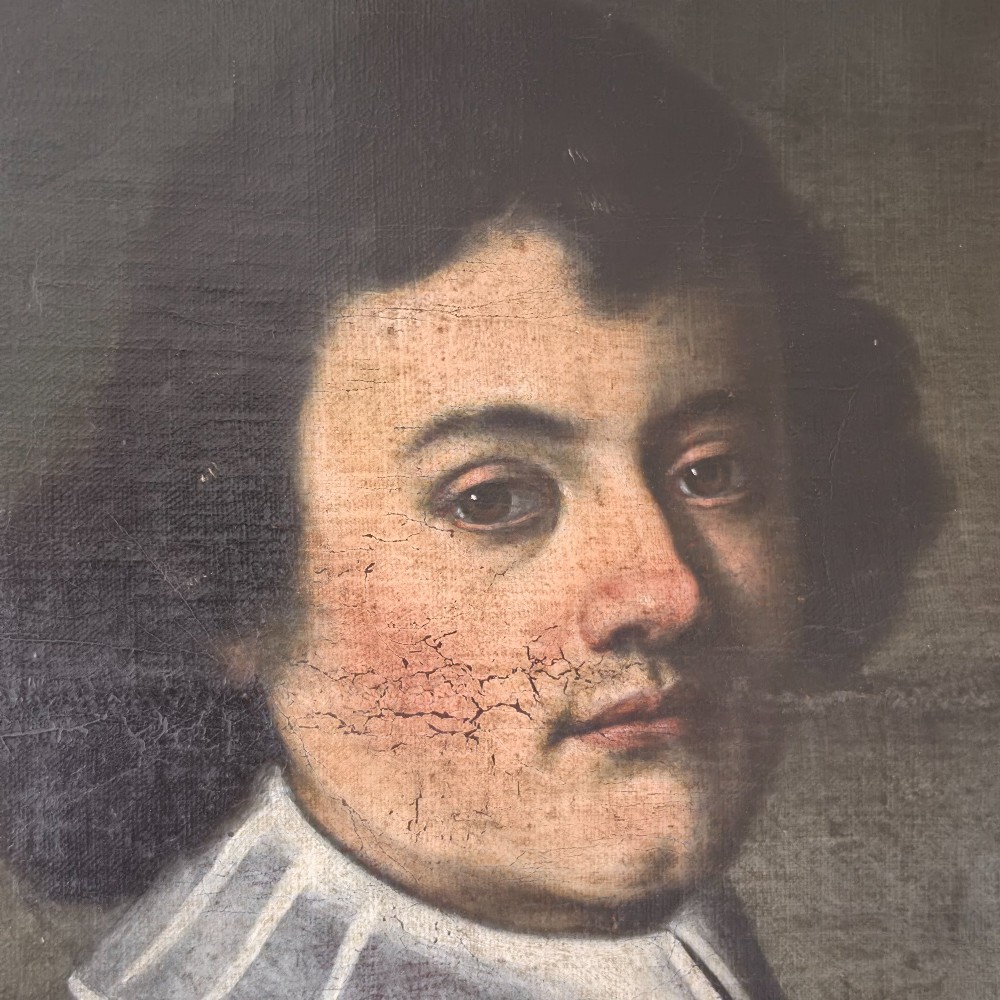 An antique oil painting depicting a 17th-century gentleman with dark hair and a white collar, presented in a dark ebonised frame. View IV