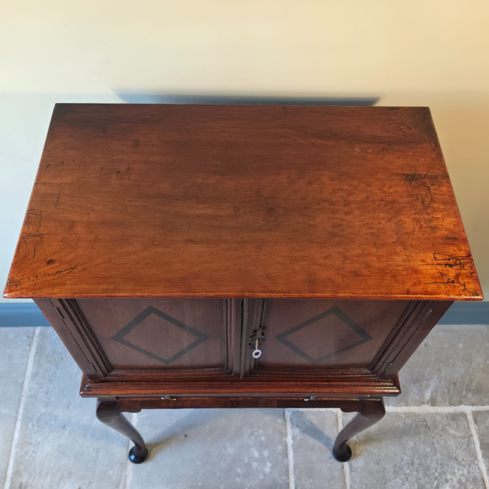 An 18th-century dark wood cabinet on stand featuring twin doors with black diamond inlay, a single lower drawer, and slender cabriole legs. View VII