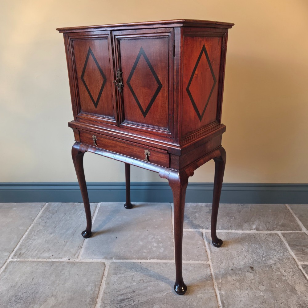 An 18th-century dark wood cabinet on stand featuring twin doors with black diamond inlay, a single lower drawer, and slender cabriole legs. View XI