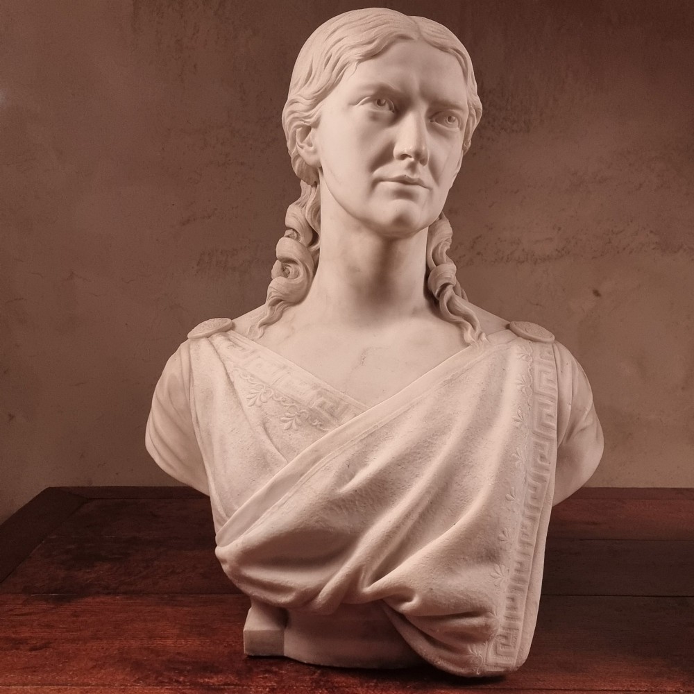 A pair of carved white marble portrait busts depicting a classical female figure on the left and a bearded man in Victorian attire on the right. View II