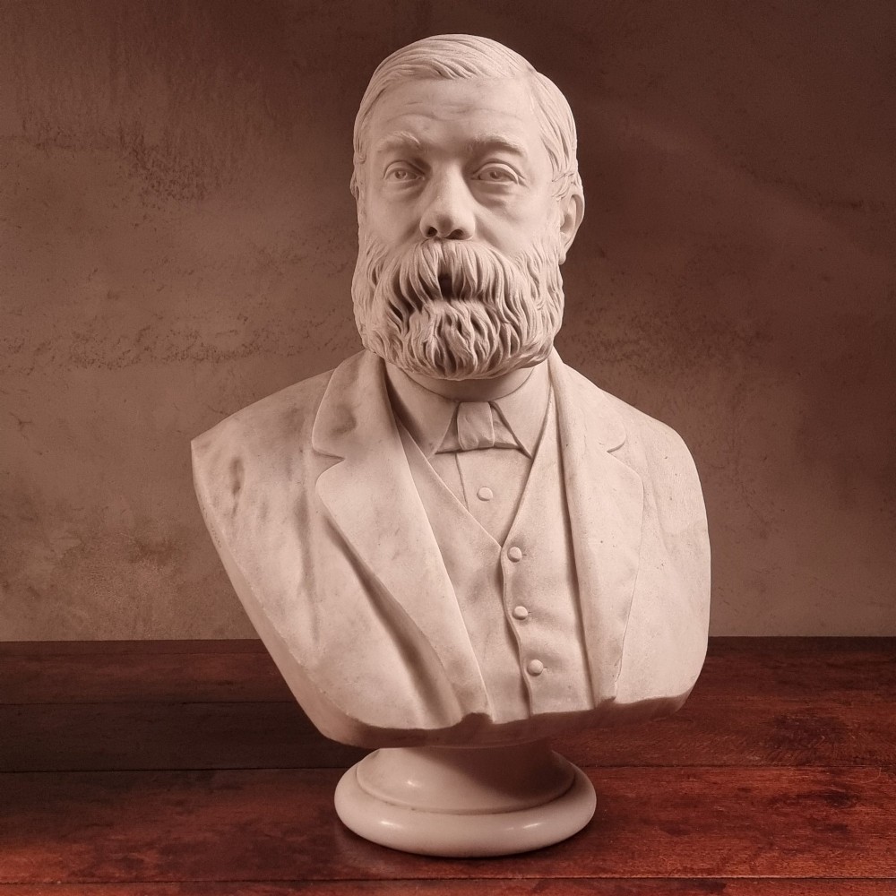 A pair of carved white marble portrait busts depicting a classical female figure on the left and a bearded man in Victorian attire on the right. View III