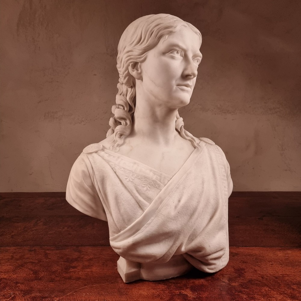 A pair of carved white marble portrait busts depicting a classical female figure on the left and a bearded man in Victorian attire on the right. View VII