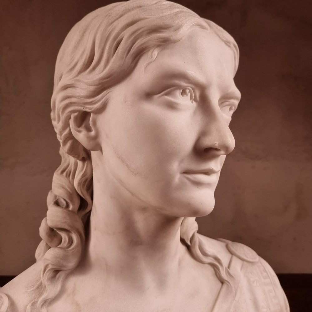 A pair of carved white marble portrait busts depicting a classical female figure on the left and a bearded man in Victorian attire on the right. View VIII